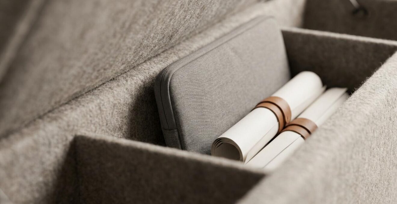 Dettaglio macro di un pouf modulare aperto che rivela uno spazio organizzato per laptop e documenti